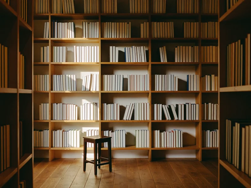 Interior de librărie independentă, cu rafturi de lemn și un taburet de citit